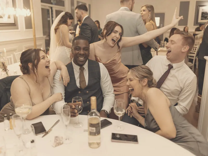 Invitados riendo alrededor de una mesa en una boda