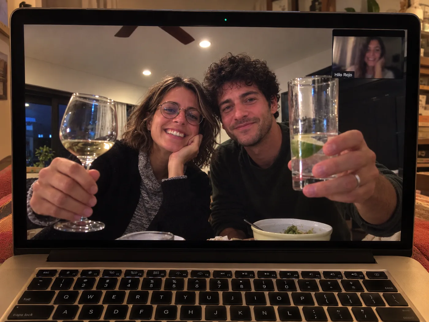 Una pareja brinda con una copa de vino y un vaso con lima durante la videollamada con Hilo Rojo
